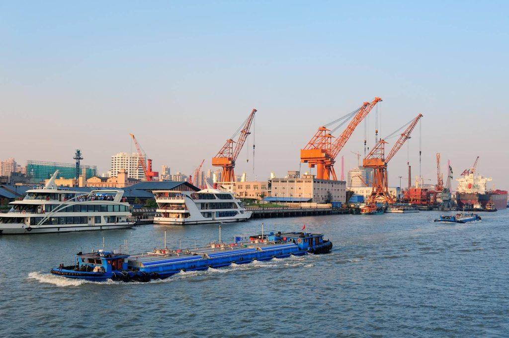 Cargo ship being loaded at a port, overseen by freight forwarders